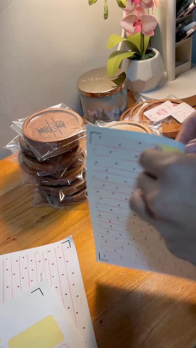 Circular wood coasters with burned designs wrapped in plastic on a wooden table.