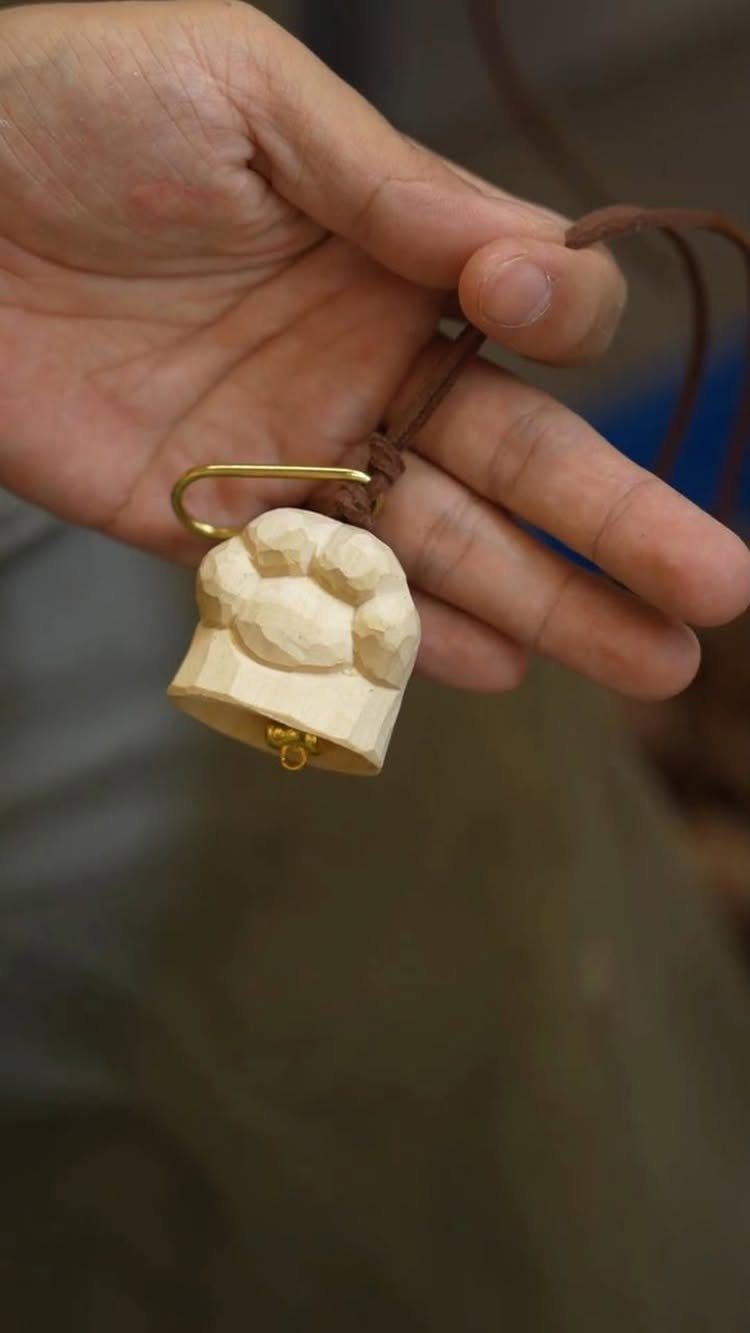 Wood Carved Ornaments: 7 Ideas for Holiday and Home 5 Small wood carved bell ornament held by a hand on a leather cord