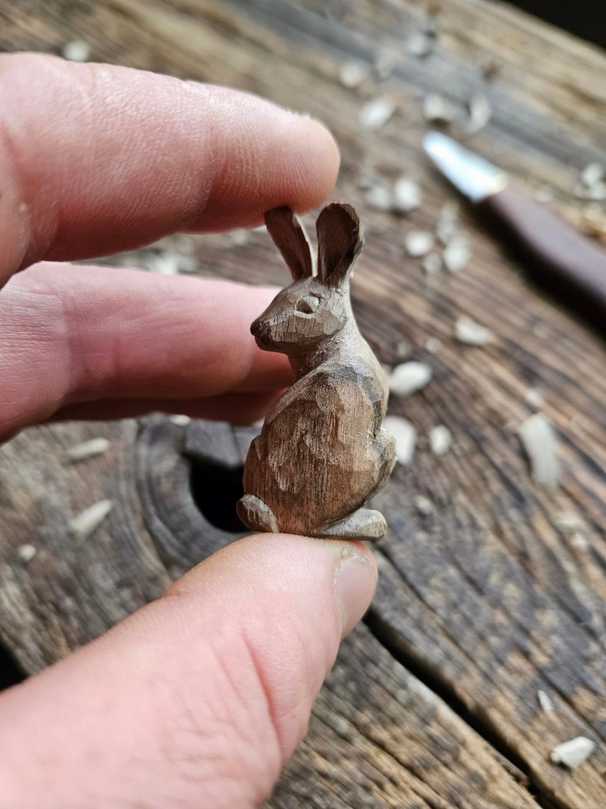 Wood Carving Animals: 14 Ideas to Try With a Knife 5 Small hand-carved wooden rabbit with long ears held by a person's fingers.