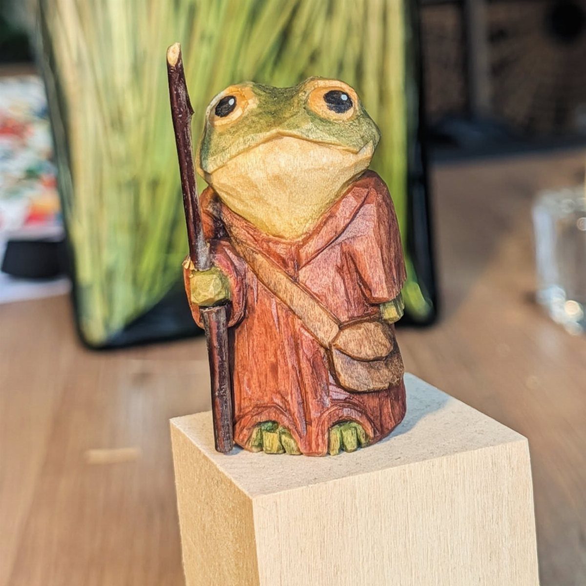 Wood Carving Animals: 14 Ideas to Try With a Knife 11 Carved wooden frog wearing a robe and holding a staff on a block.