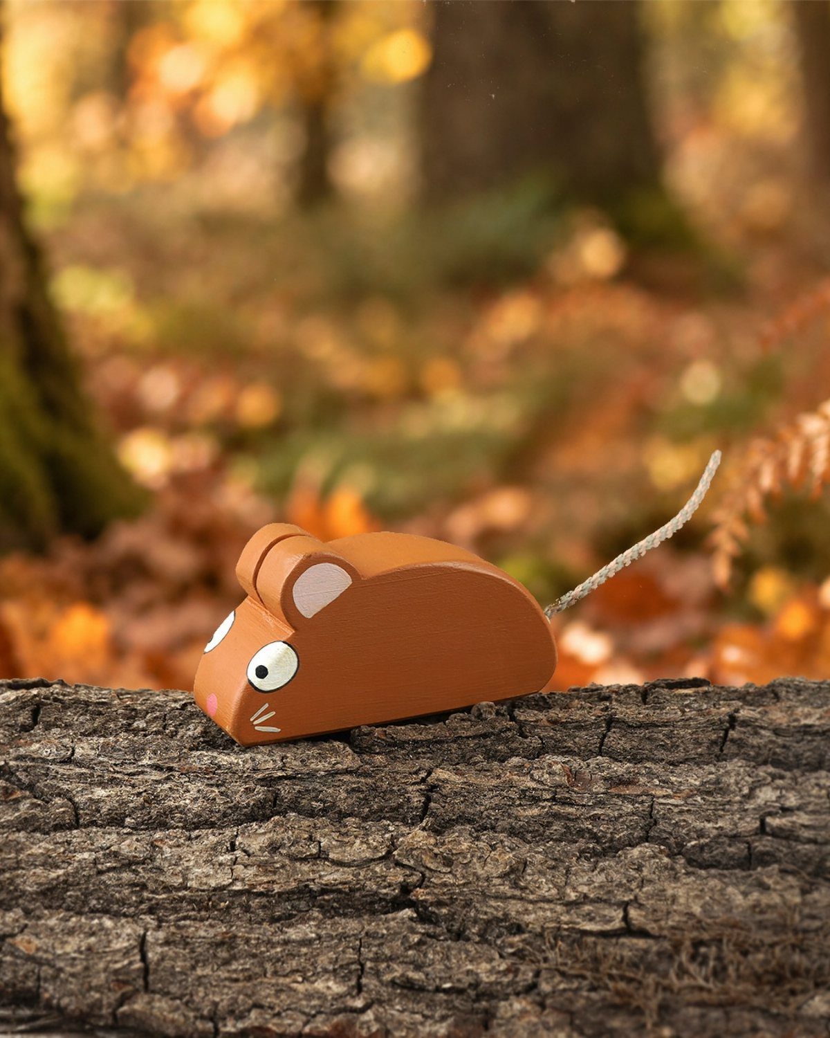 Wood Carving Animals: 14 Ideas to Try With a Knife 10 Orange wooden mouse carving resting on a textured log in an autumn forest.