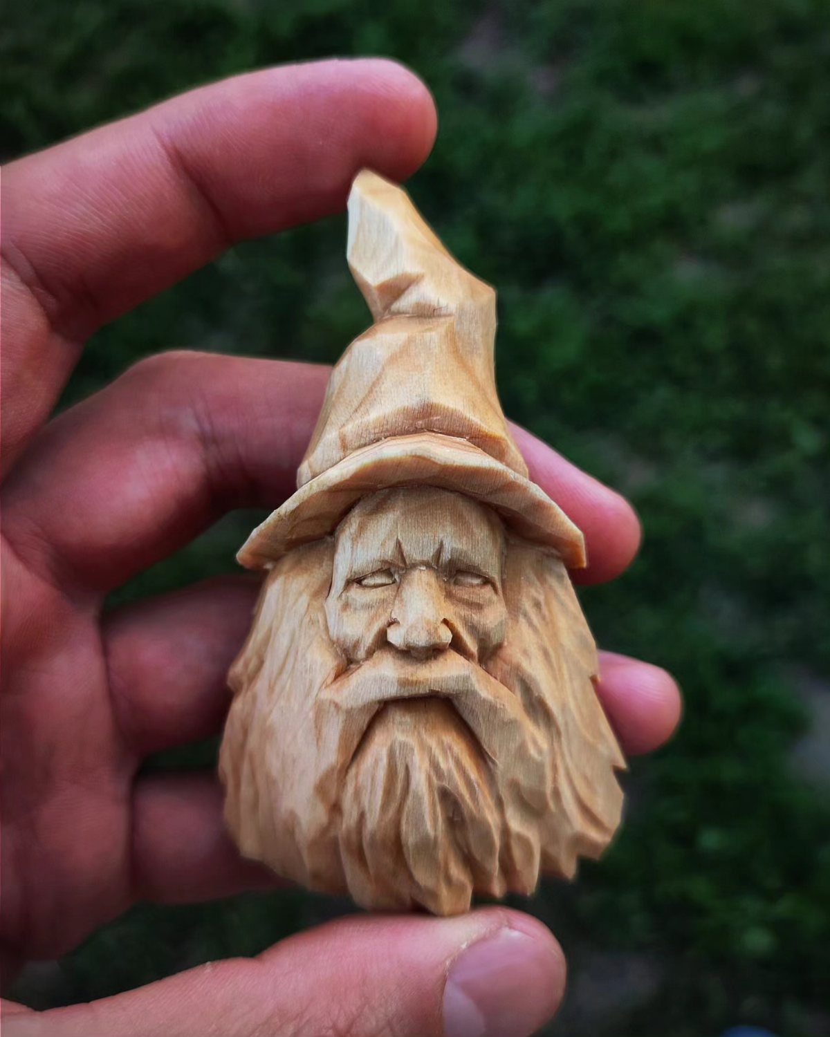 Small wooden carving of a bearded character with a pointed hat held in hand.