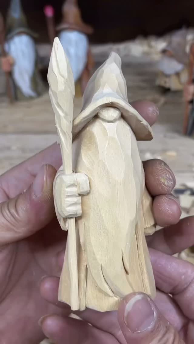Hand-carved wooden figure of a hooded character with a beard and staff.