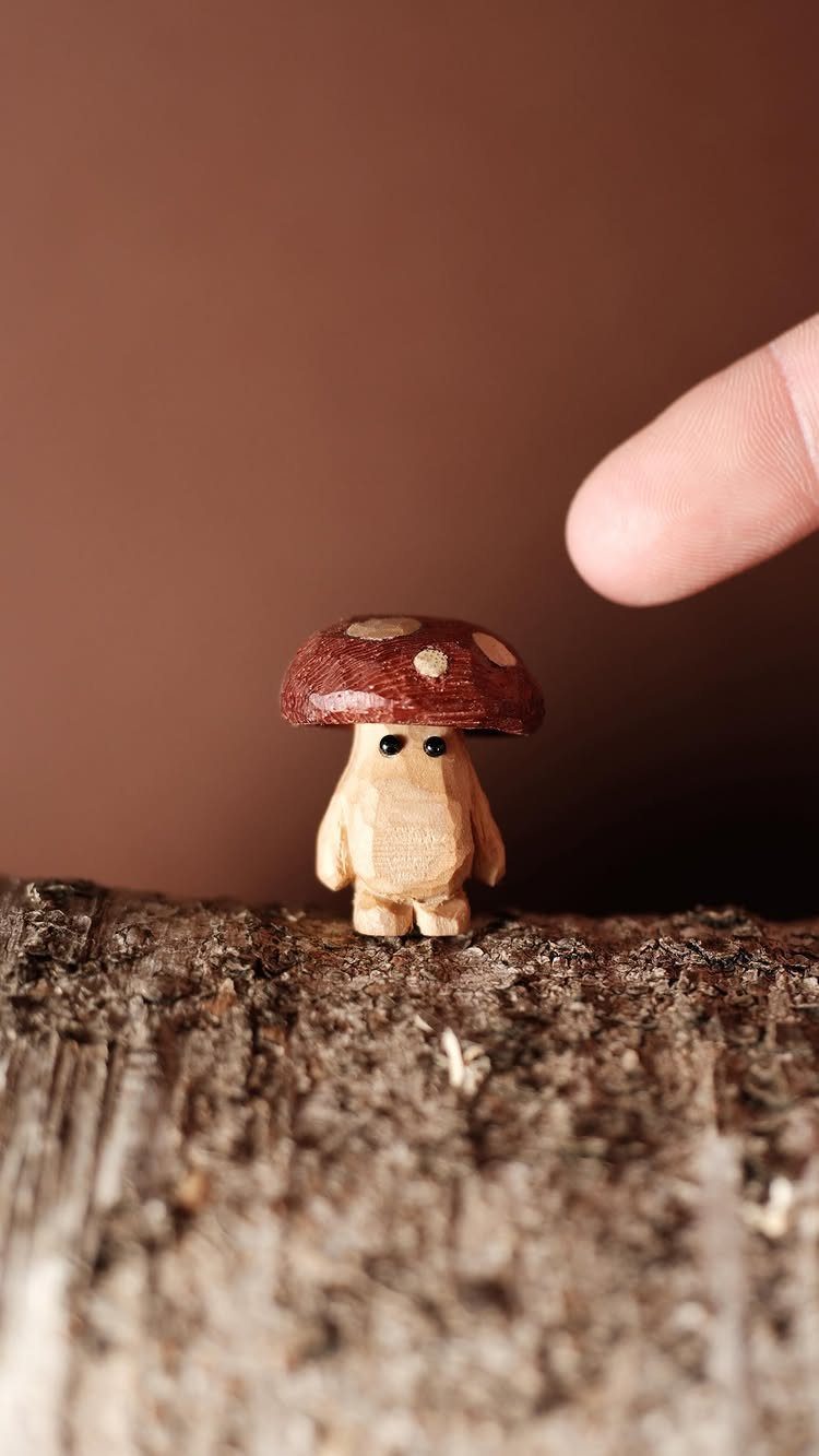 Small wooden carved mushroom character standing on a piece of natural tree bark.