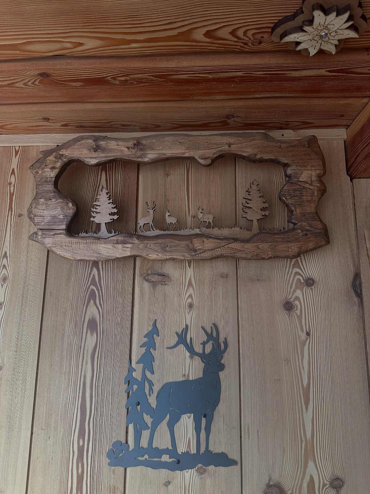 Wood carving of deer and pine trees set within a rustic wooden frame
