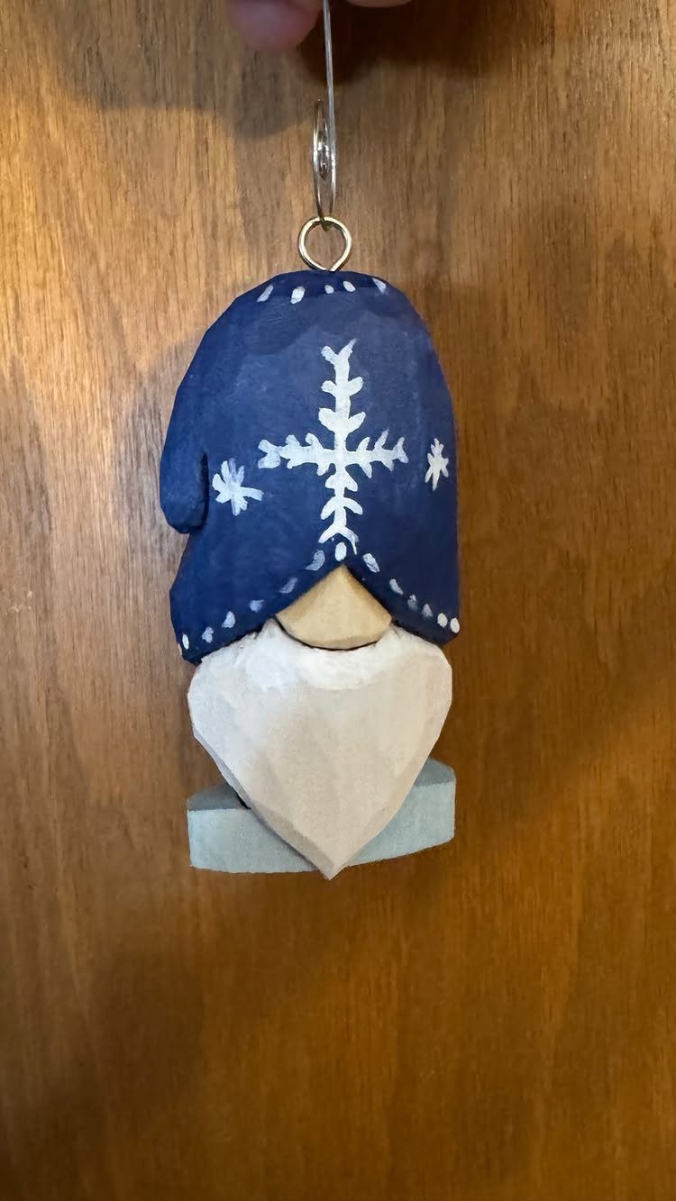 Hand-carved wooden Christmas ornament of a bearded figure wearing a blue snowflake hat.