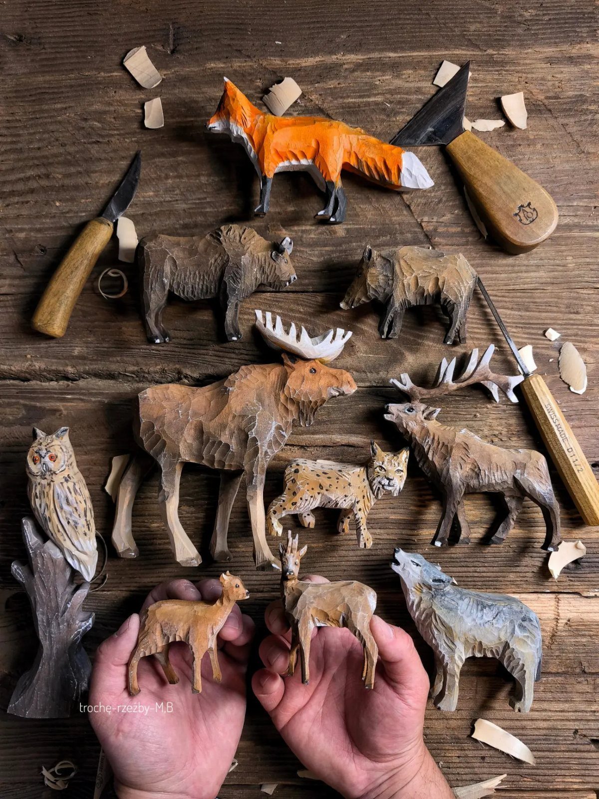 Hand-carved wooden animals and carving tools on a rustic dark wood workbench