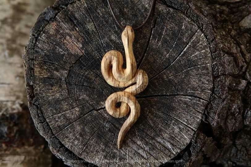 6 Wood Carving Snake Ideas for Every Skill Level 6 Hand-carved wooden snake pendant resting on a rustic tree stump cross-section