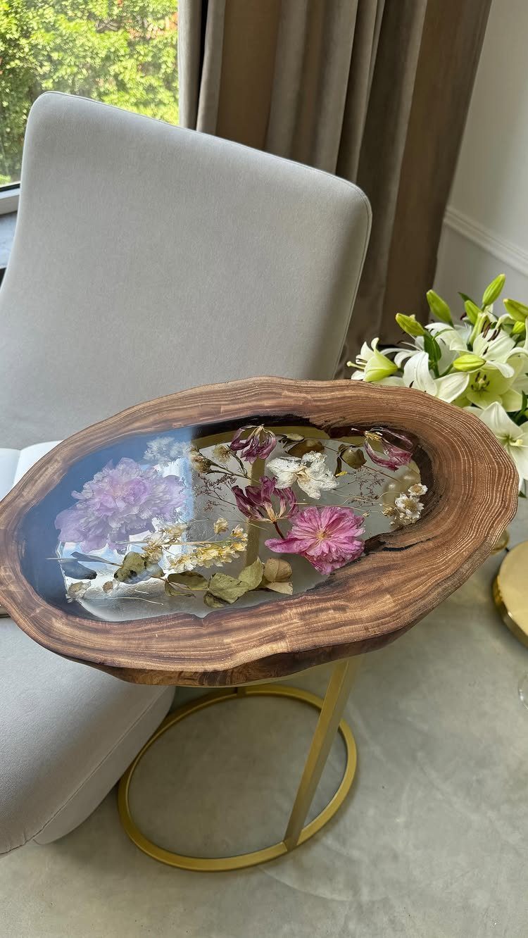Natural wood slab side table with resin inlay containing dried pink and white flowers.