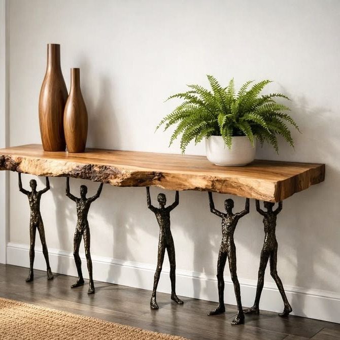 Live-edge wooden console table supported by bronze human figure sculptures against a white wall