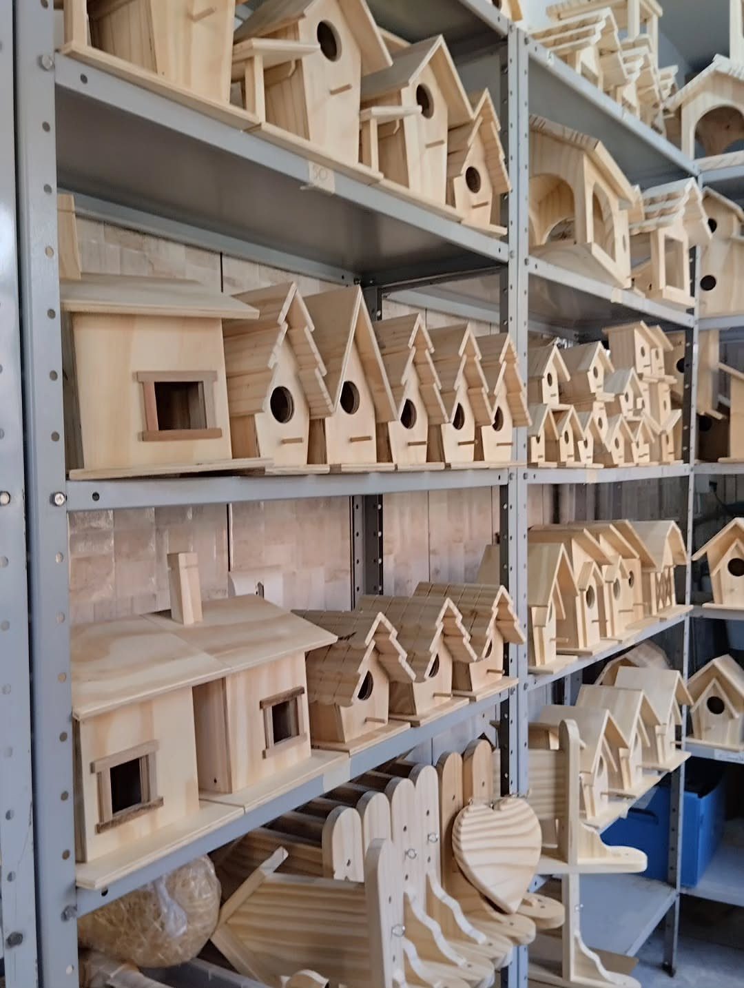 14 Wood Ideas to Sell: Easy Projects for Craft Fairs 10 Wooden birdhouses of various designs displayed on grey metal industrial shelving units.