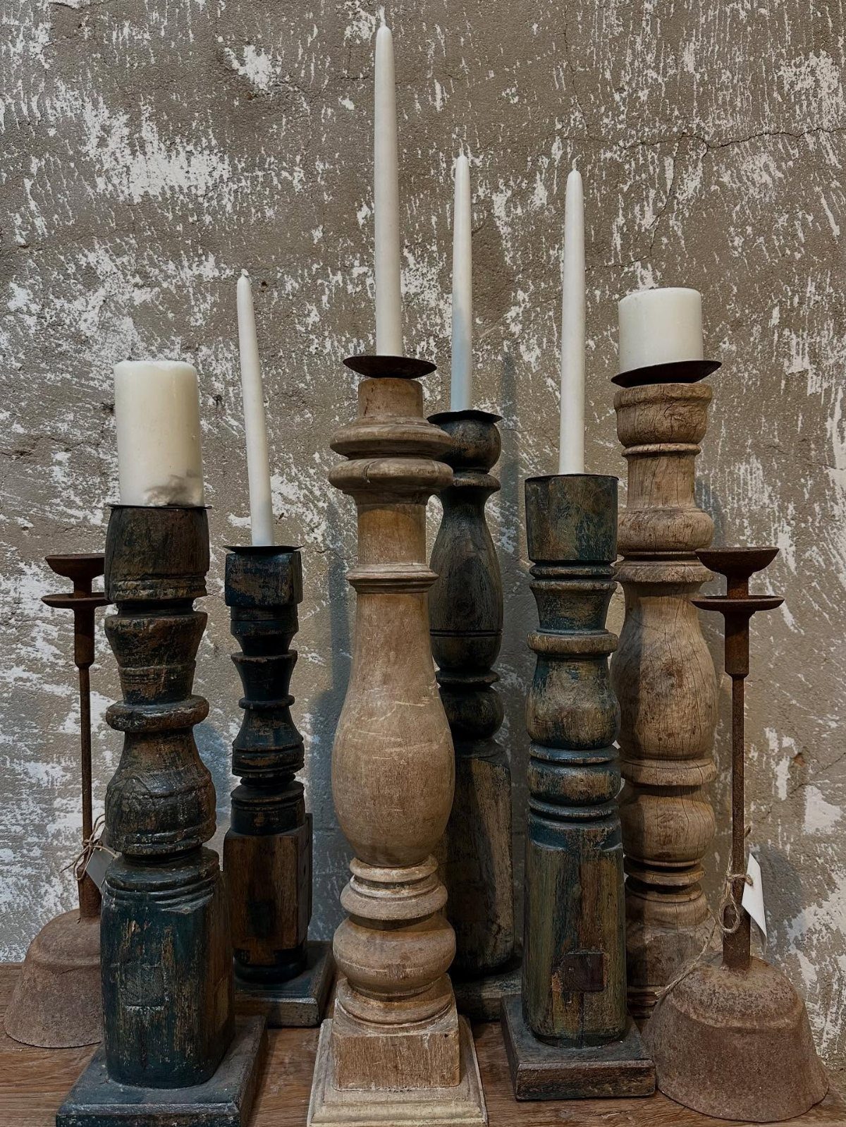 14 Wood Ideas to Sell: Easy Projects for Craft Fairs 5 Wooden candle holders of various heights and finishes holding white candles against a grey wall.