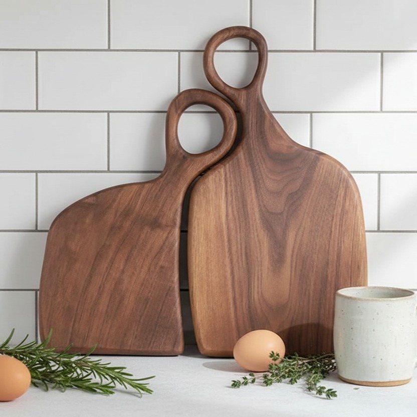 14 Wood Ideas to Sell: Easy Projects for Craft Fairs 2 Two wooden cutting boards with handles leaning against a white tiled kitchen wall.