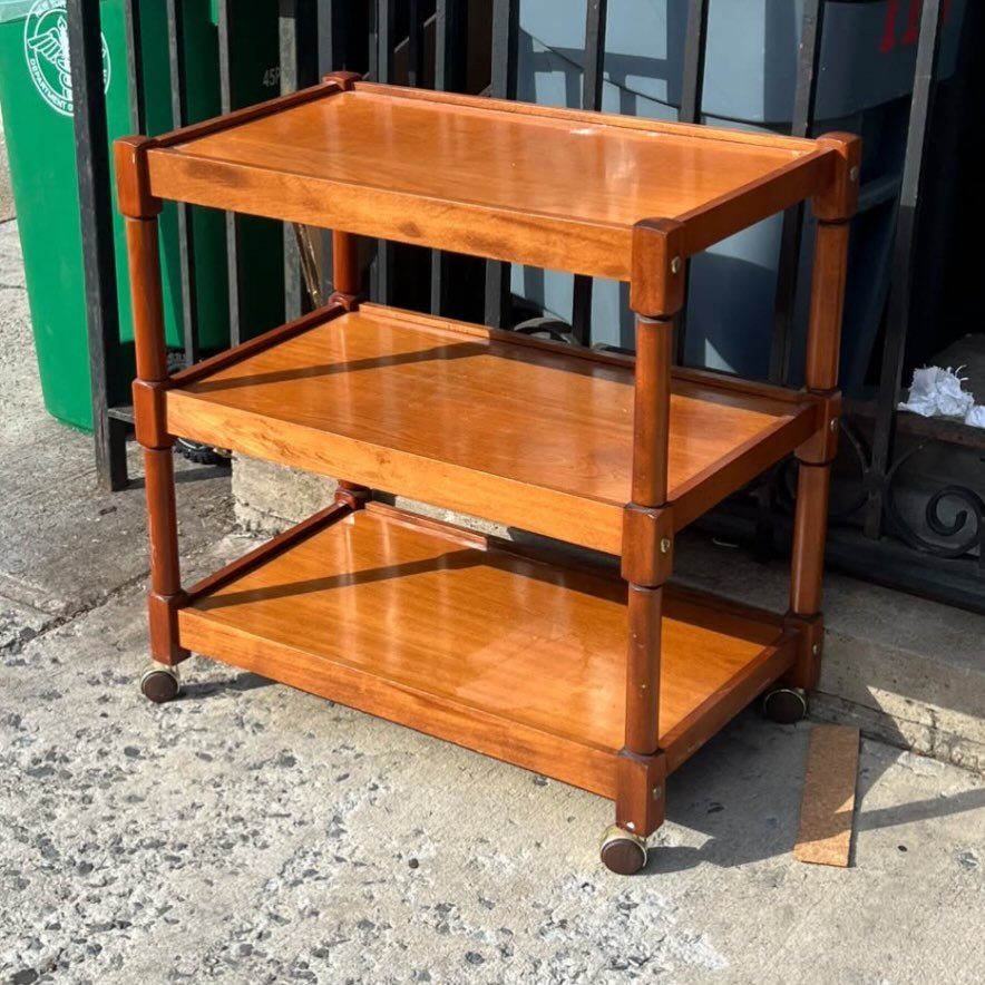 14 Wood Ideas to Sell: Easy Projects for Craft Fairs 14 Three-tiered polished brown wooden rolling cart with caster wheels on concrete pavement.