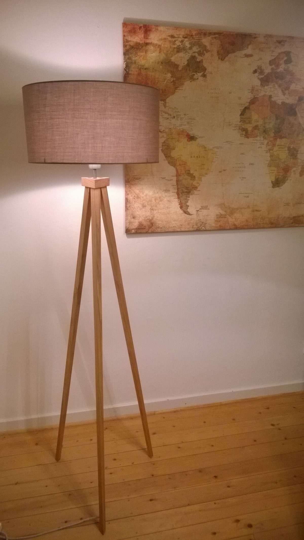 Wood Lamp Design: 14 Table, Floor and Pendant Ideas 12 Tripod floor lamp with wooden legs and beige fabric shade against a white wall.