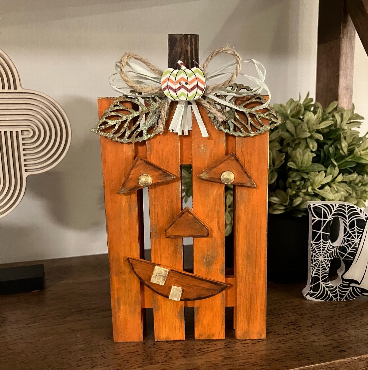17 Wood Pallet Projects for Furniture, Decor, and Garden 17 Orange wooden pallet pumpkin decoration with a carved face and decorative bow.