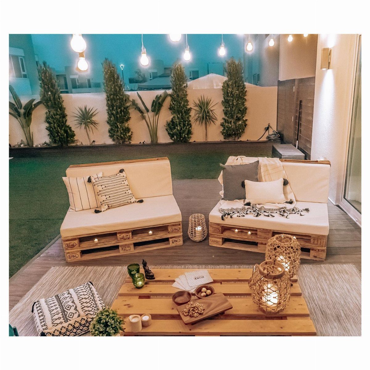 17 Wood Pallet Projects for Furniture, Decor, and Garden 14 Wooden pallet sofas with cream cushions and a pallet coffee table on a patio.
