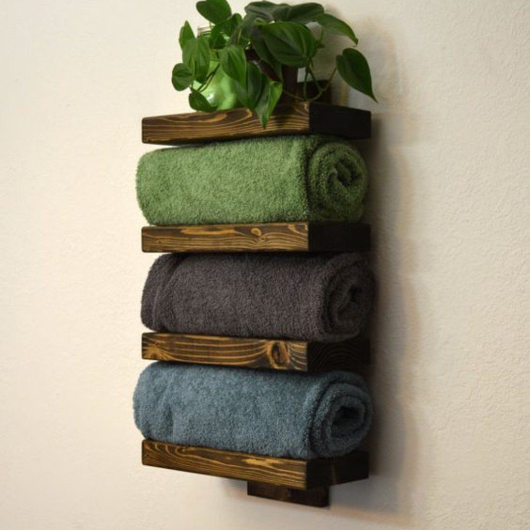 17 Wood Pallet Projects for Furniture, Decor, and Garden 7 Rustic wooden pallet towel rack holding rolled green, grey, and blue towels with plant.