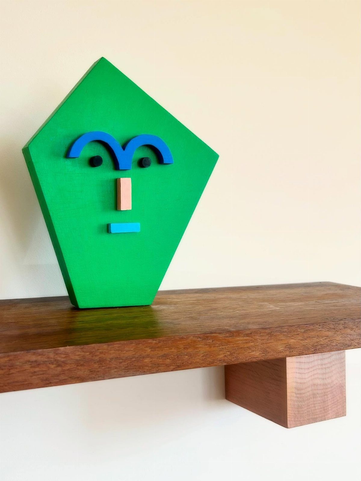 Wood Piece Art Ideas: 25 Designs for Walls and Shelves 7 Green geometric wooden face sculpture with blue and brown accents on a wooden shelf