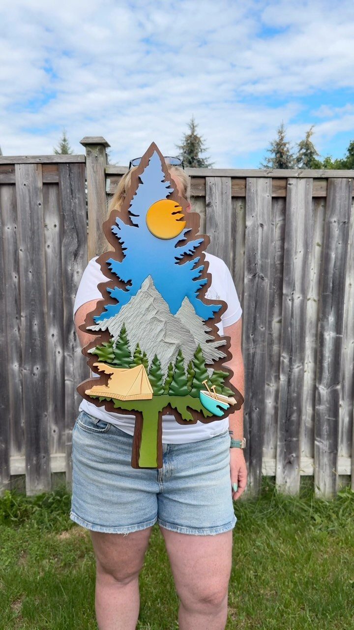 Wood Piece Art Ideas: 25 Designs for Walls and Shelves 19 Layered wooden art piece shaped like a pine tree featuring mountains and camping scenes.