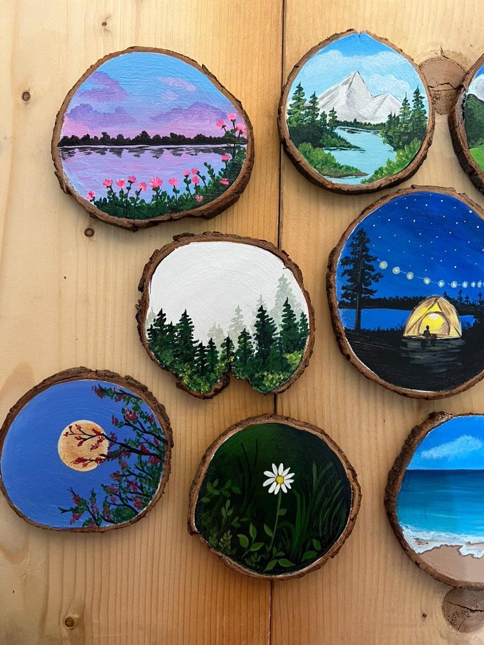 Wood Piece Art Ideas: 25 Designs for Walls and Shelves 5 Painted landscape scenes on round wooden slices with natural bark edges.