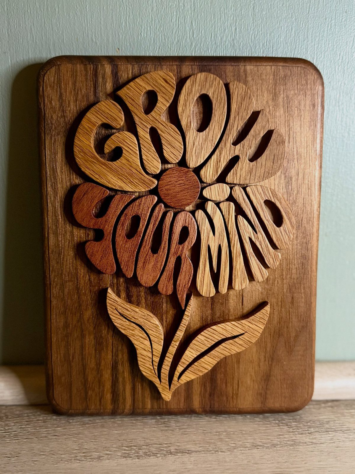 Wood Piece Art Ideas: 25 Designs for Walls and Shelves 6 Wooden plaque with carved 3D letters spelling Grow Your Mind in a flower shape.