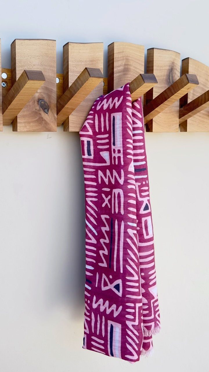Wooden wall-mounted coat rack with a purple patterned scarf hanging from one peg.