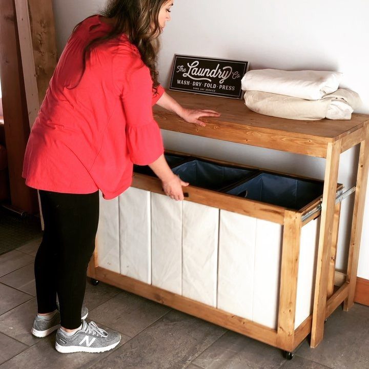 Wooden laundry folding table with blue bins and white towels on top.