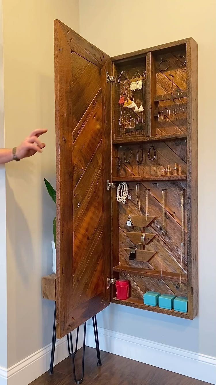 Wall mount jewelry cabinet made of brown wood with open door displaying jewelry.