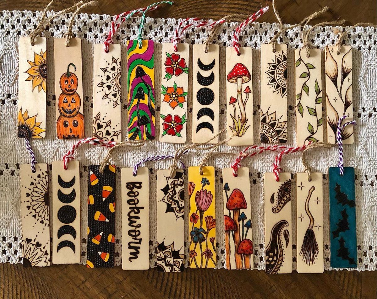 Wooden bookmarks with colorful illustrations and string loops resting on white lace fabric.