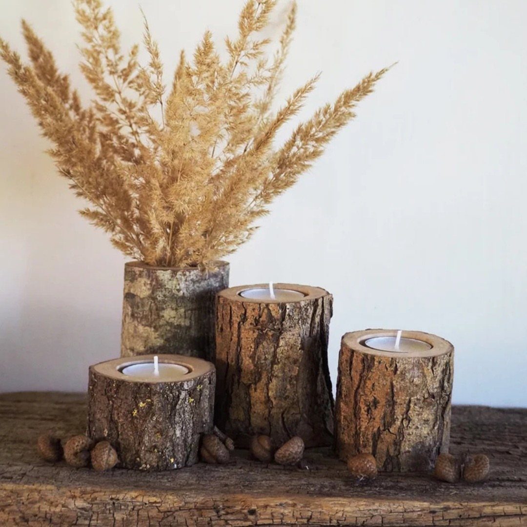 Three rustic log candle holders with tea lights and dried pampas grass.
