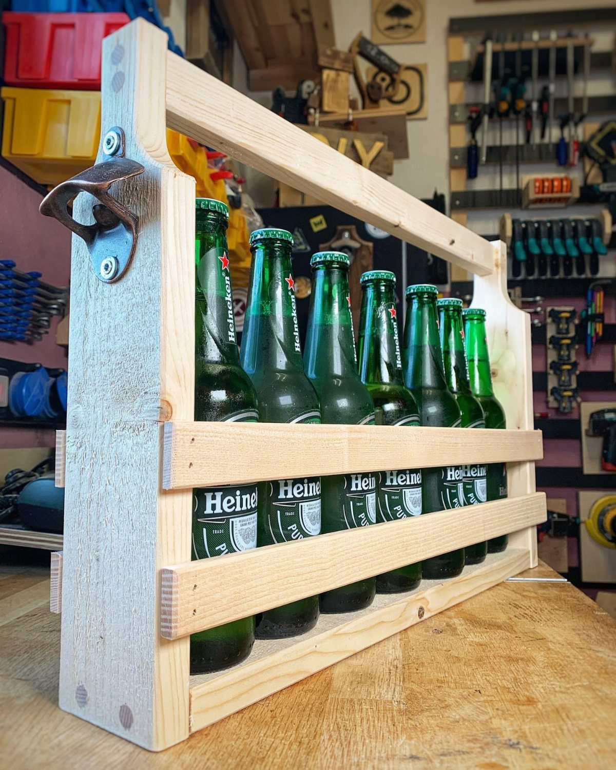 18 Wood Projects with Plans for Every Skill Level 7 Wooden beer caddy holding green glass bottles on a workshop workbench