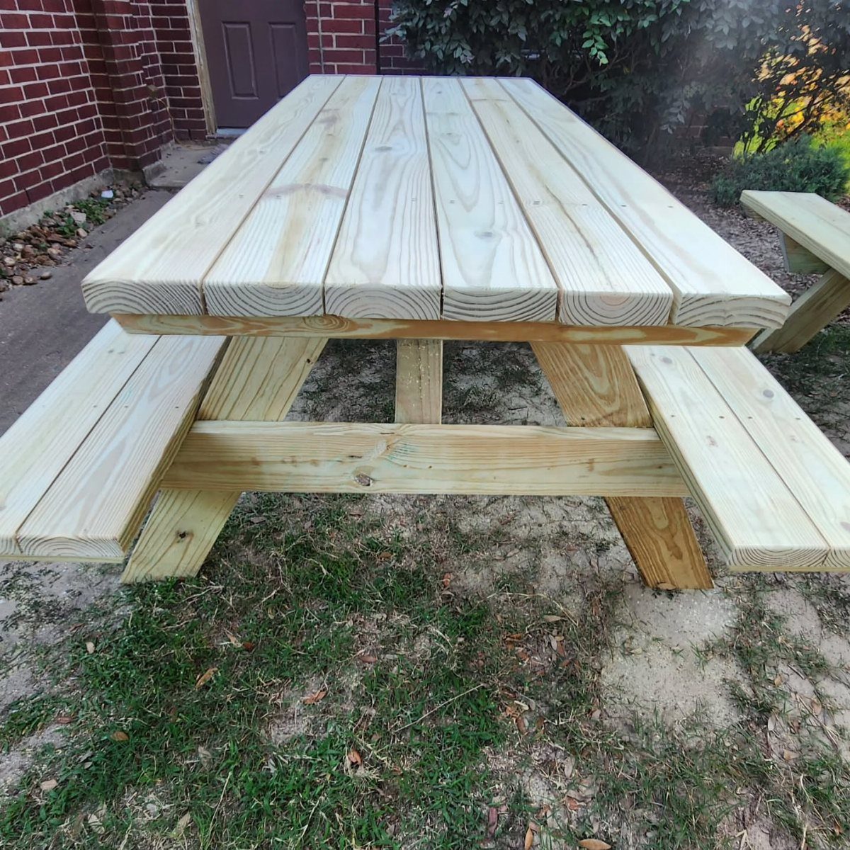 18 Wood Projects with Plans for Every Skill Level 8 Wooden picnic table with attached benches sitting on a grassy outdoor area.