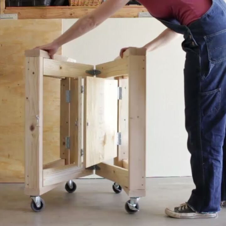 18 Wood Projects with Plans for Every Skill Level 9 Folding wooden workbench on wheels being adjusted by a person in blue overalls.
