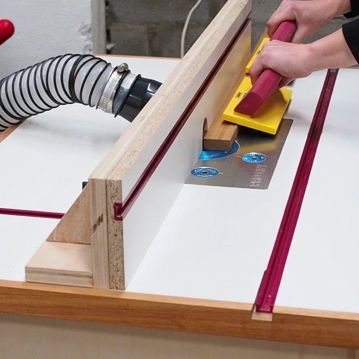 Wood Router Table Ideas: 6 Setups for Your Workshop 1 Hands using a yellow push paddle on a white wood router table.
