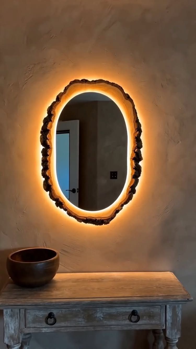Backlit oval mirror with a natural wood slice frame on a textured wall