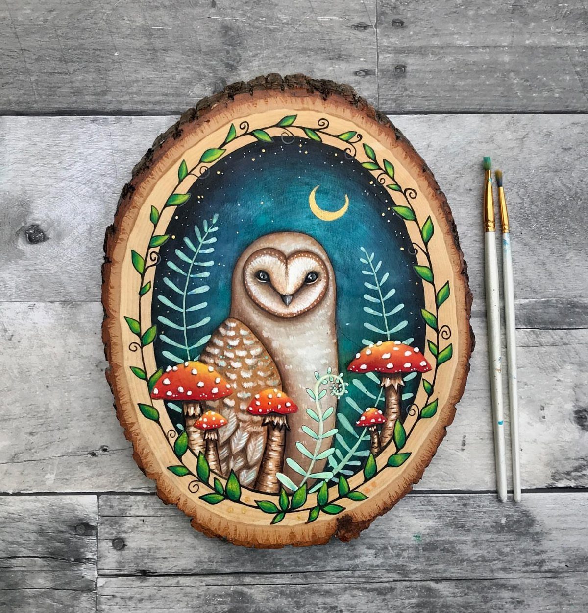 Painted barn owl with mushrooms and moon on a natural wood slice.