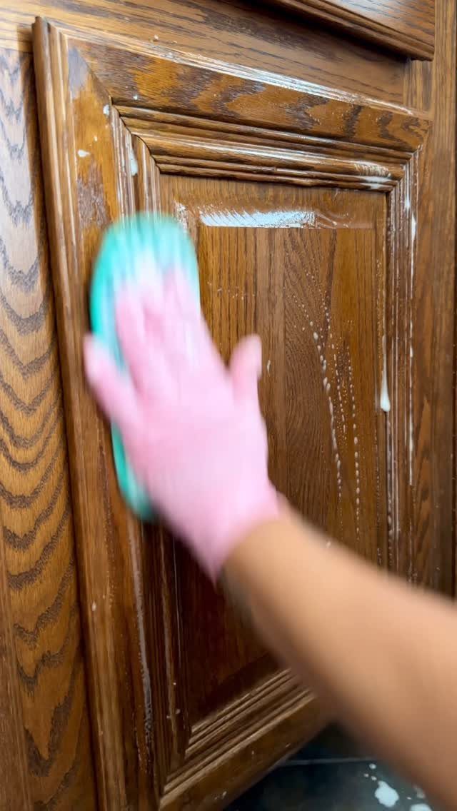 Can You Apply Wood Stain Over Stain? 3 Ideas That Help 2 Hand in pink glove scrubbing brown wooden cabinet door with turquoise sponge