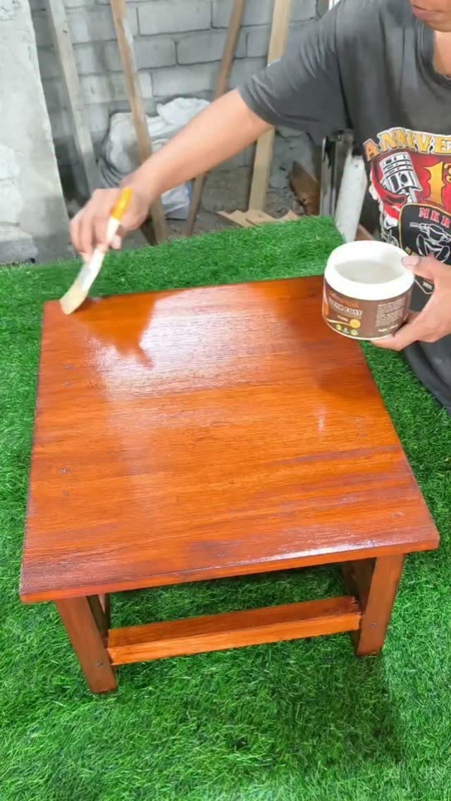 Can You Apply Wood Stain Over Stain? 3 Ideas That Help 1 Person applying clear seal coat to a reddish-brown stained wooden table with a brush.