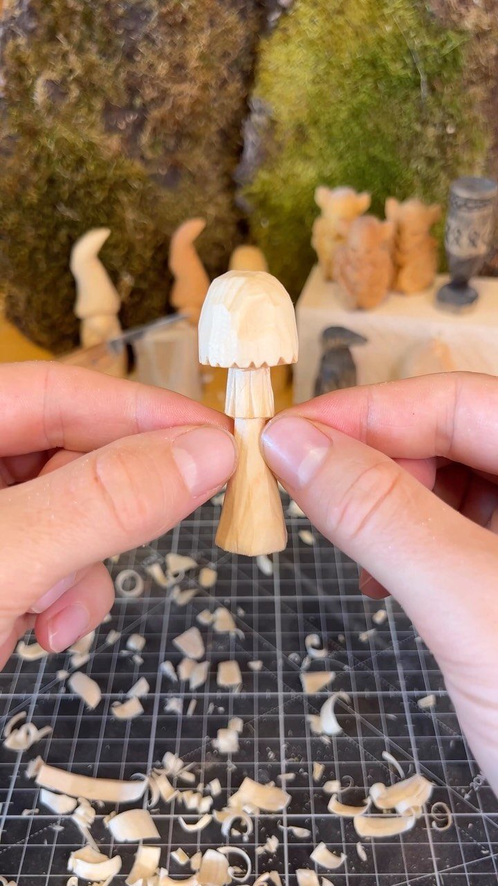 Wood Statue Carving: 6 Ideas from Mushrooms to Bears 1 Small hand-carved wooden mushroom held by hands over a workspace with wood shavings.