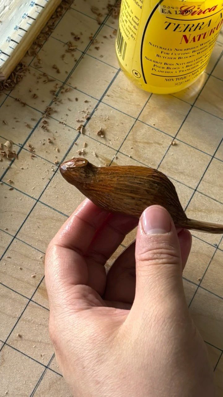 Wood Statue Carving: 6 Ideas from Mushrooms to Bears 3 Small carved wooden animal held by a hand over a gridded cutting mat.