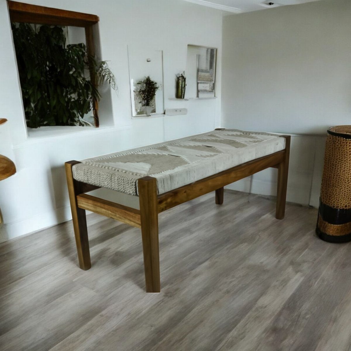 Wooden bench with a woven patterned seat in a bright white room.