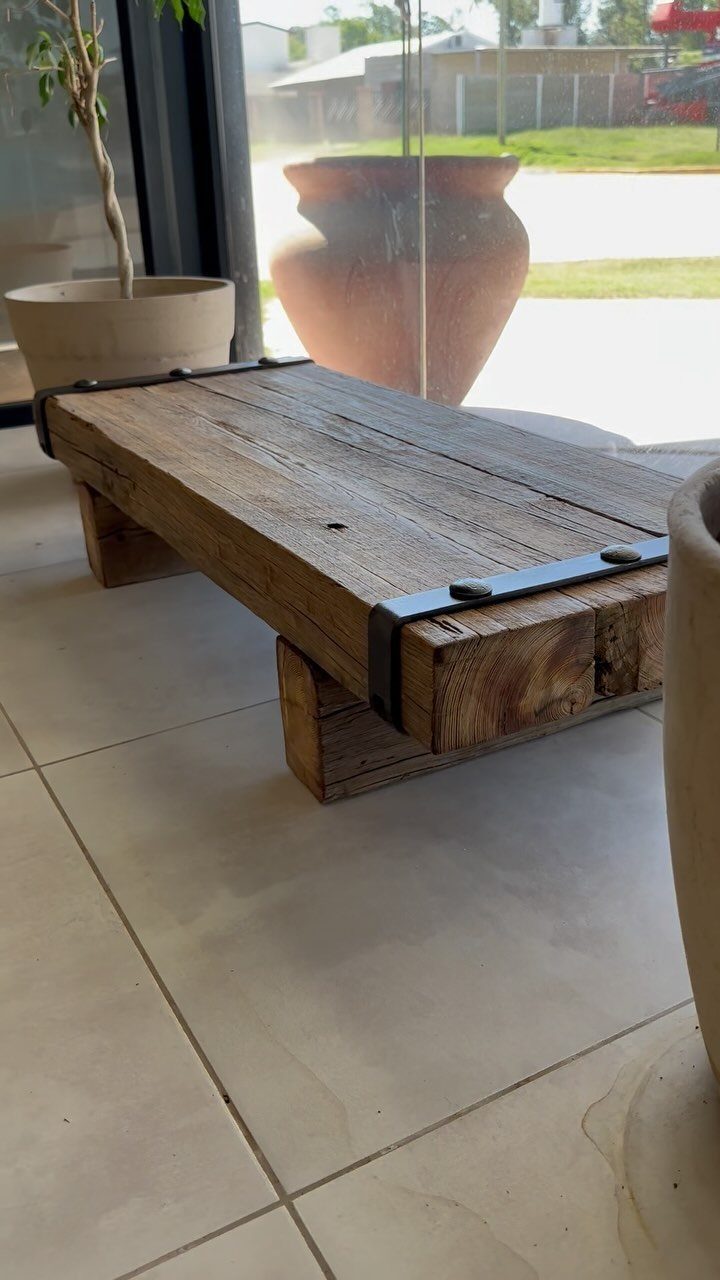 Rustic wooden bench made of thick weathered planks with black metal corner brackets.