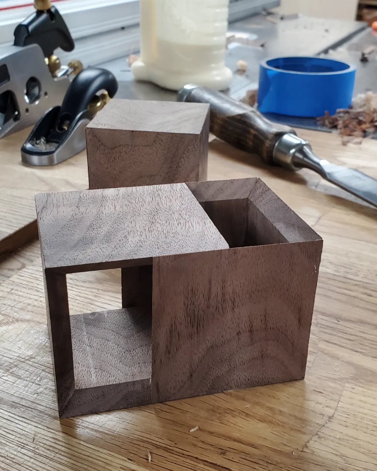 7 Wooden Box Designs for Jewelry, Tissue and Storage 4 Small dark brown wooden boxes with geometric cutouts on a woodworking workbench.