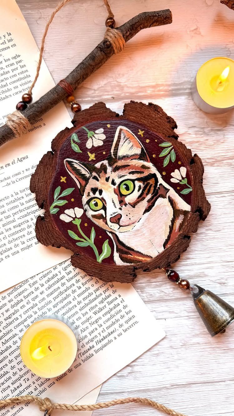 Wooden Cat Face Ideas: 5 Cutouts, Carvings and Wall Art 5 Painted cat face on a rustic wooden slice with white flowers and candles.