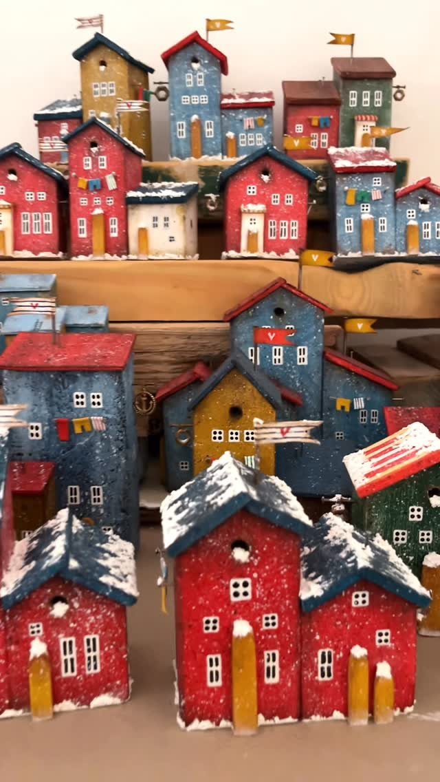Small colorful wooden houses with snow on roofs arranged as a Christmas village.