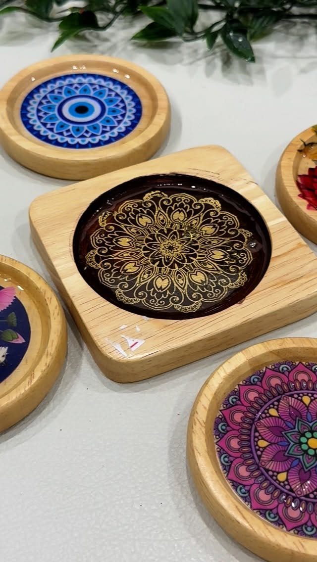 Wooden coasters with colorful mandala designs in recessed circular centers on a light surface.