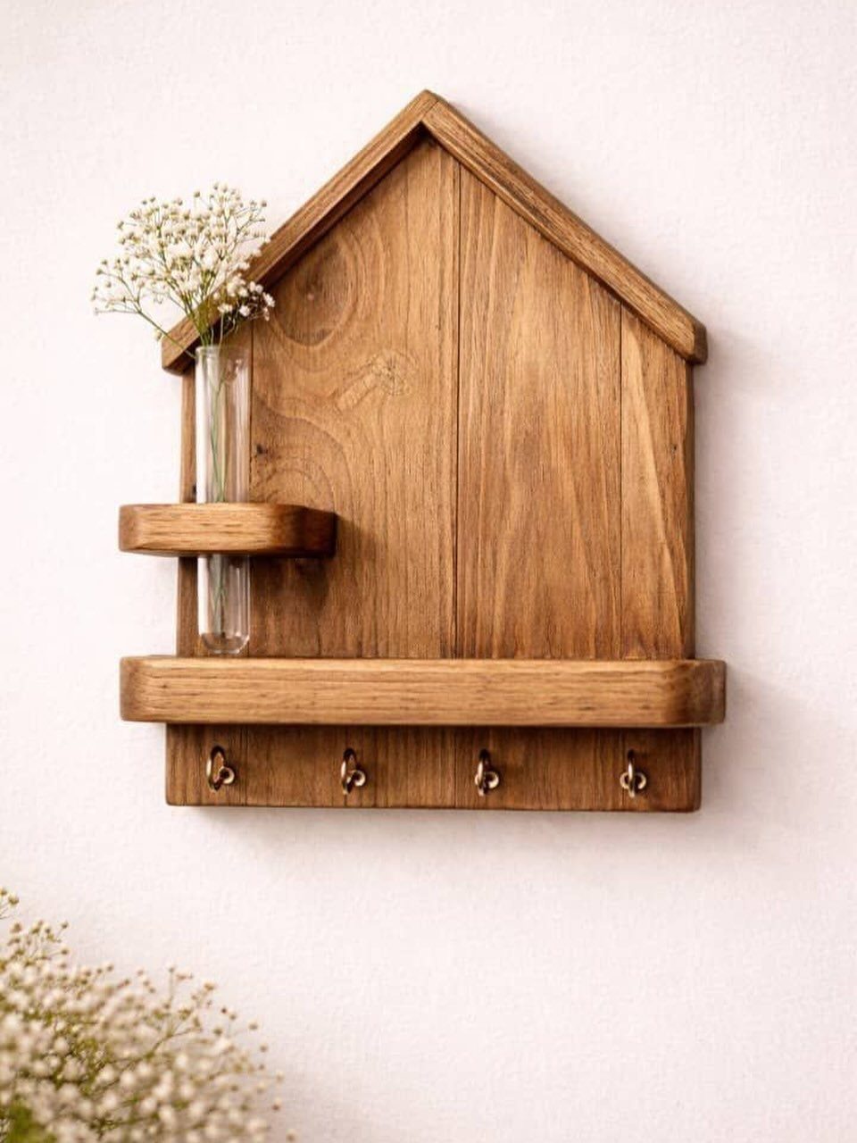 House-shaped wooden entryway organizer with a small shelf and four metal hooks.