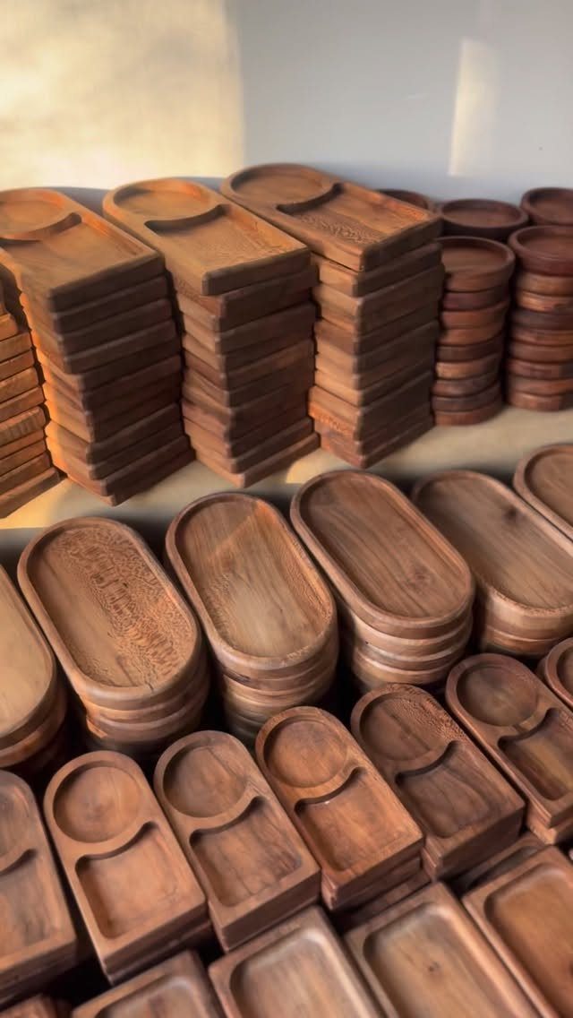 Handcrafted wooden trays and bowls stacked on shelves in a bright room.