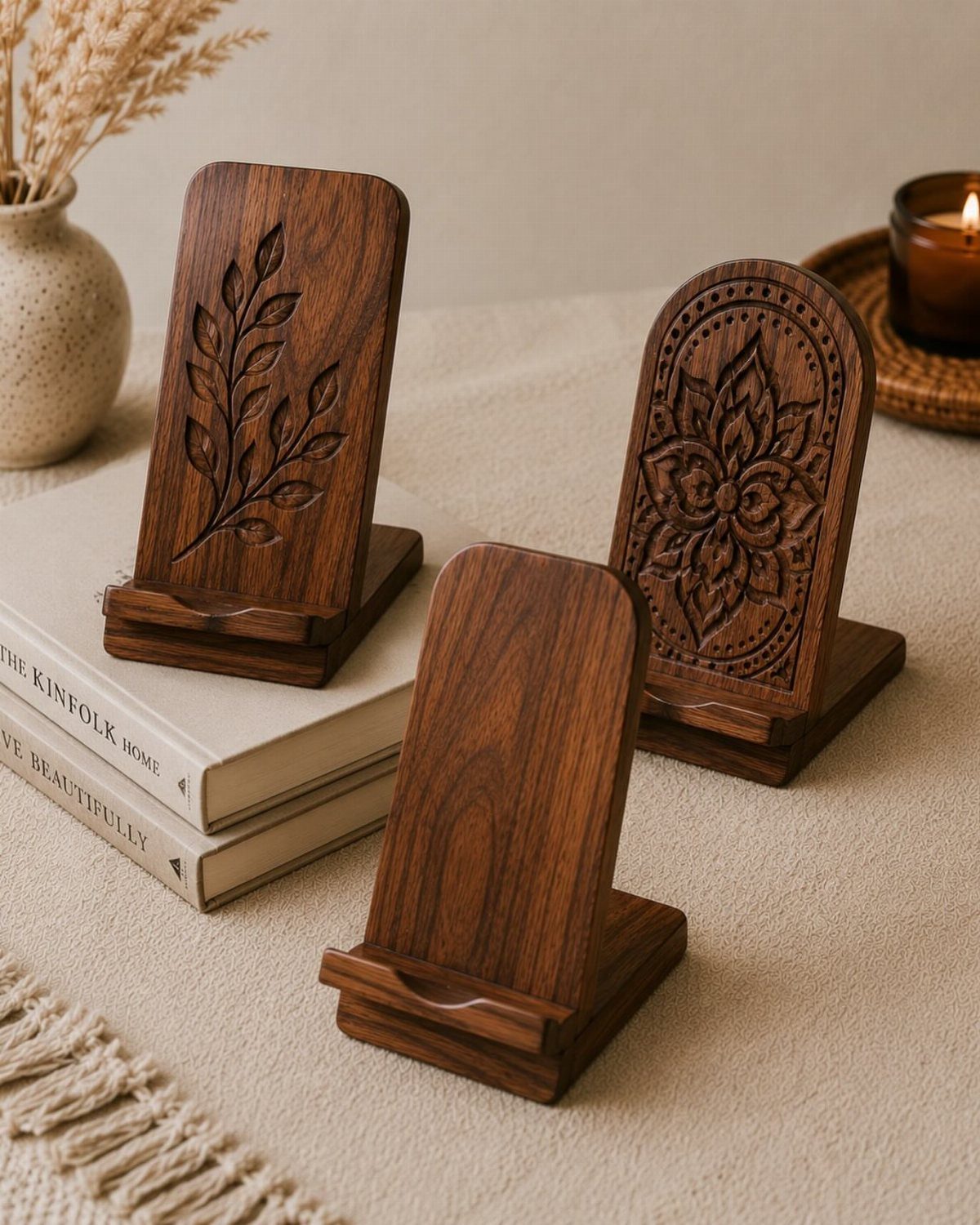 Three carved dark brown wooden phone stands displayed on a white tabletop surface.